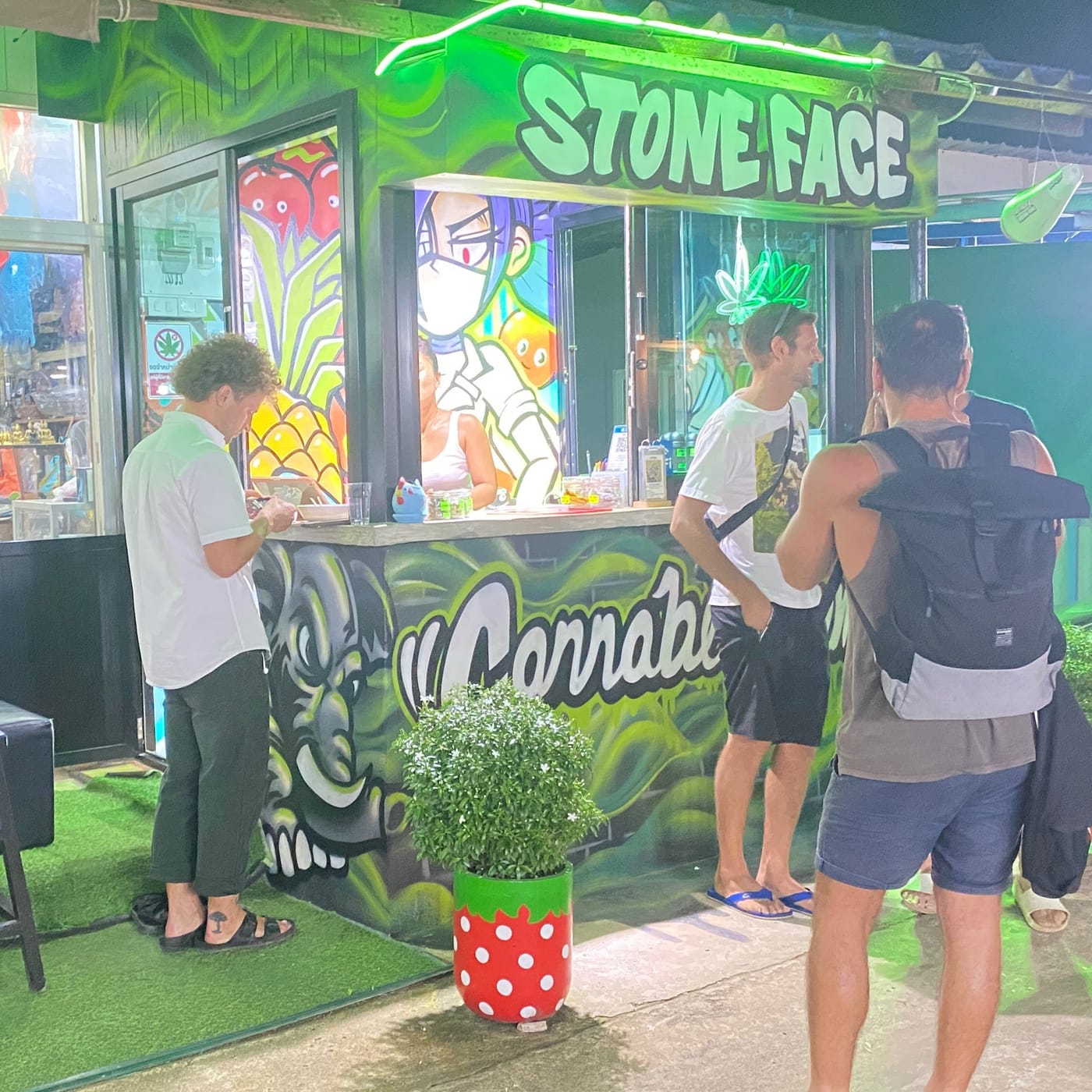 Customers being served at the graffiti-painted counter under the Stone Face sign